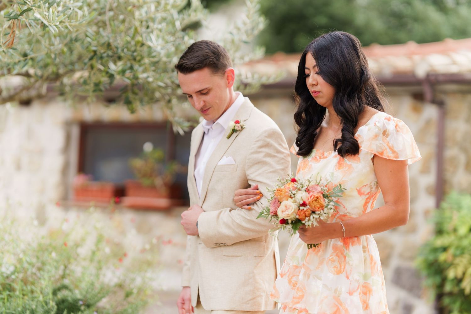 Wedding party members sharing joyful moments in an outdoor garden setting.