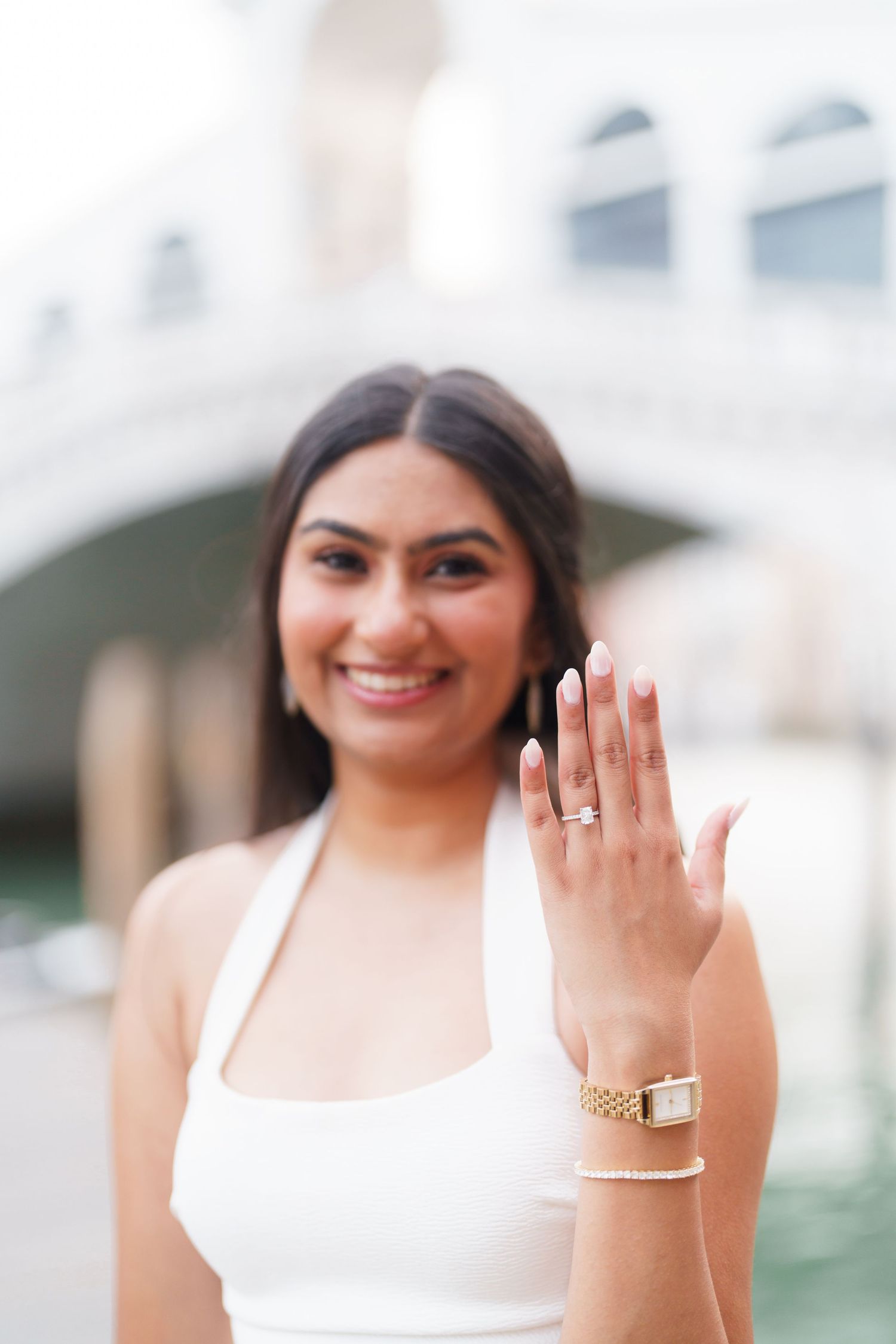 A person in a white sleeveless top shows off an engagement ring in a series of four connected photos.
