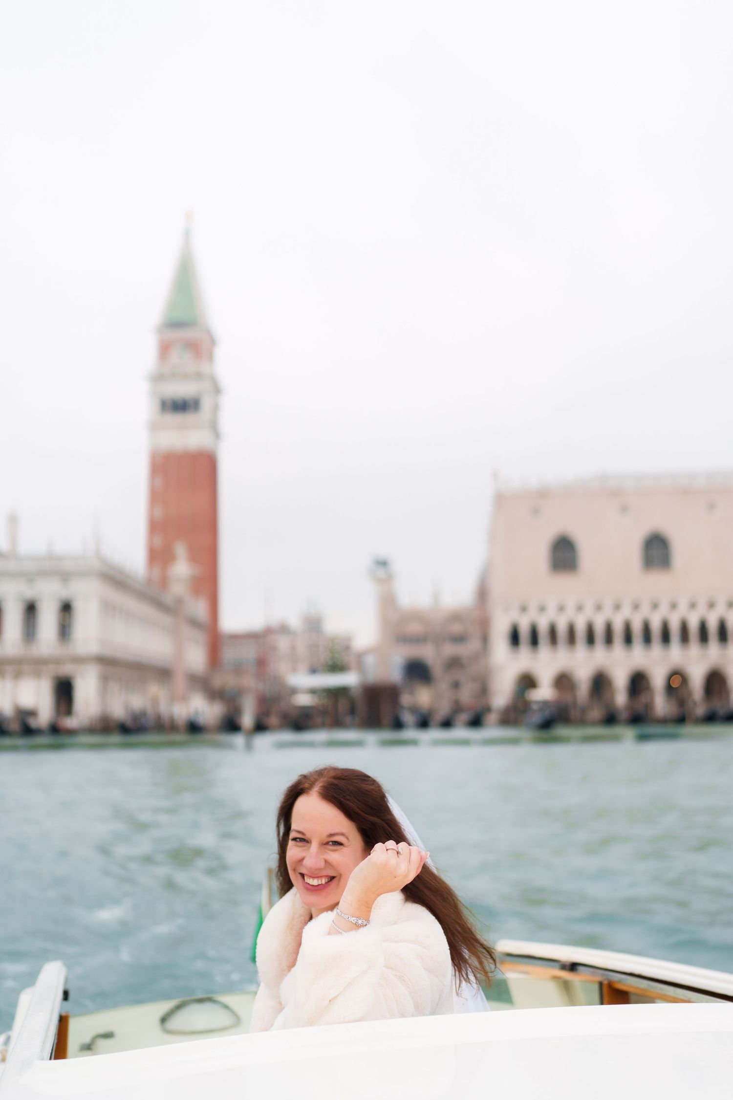 Tourist enjoying a boat ride on Venice's Grand Canal with St Mark's Campanile and Doge's Palace in the background.