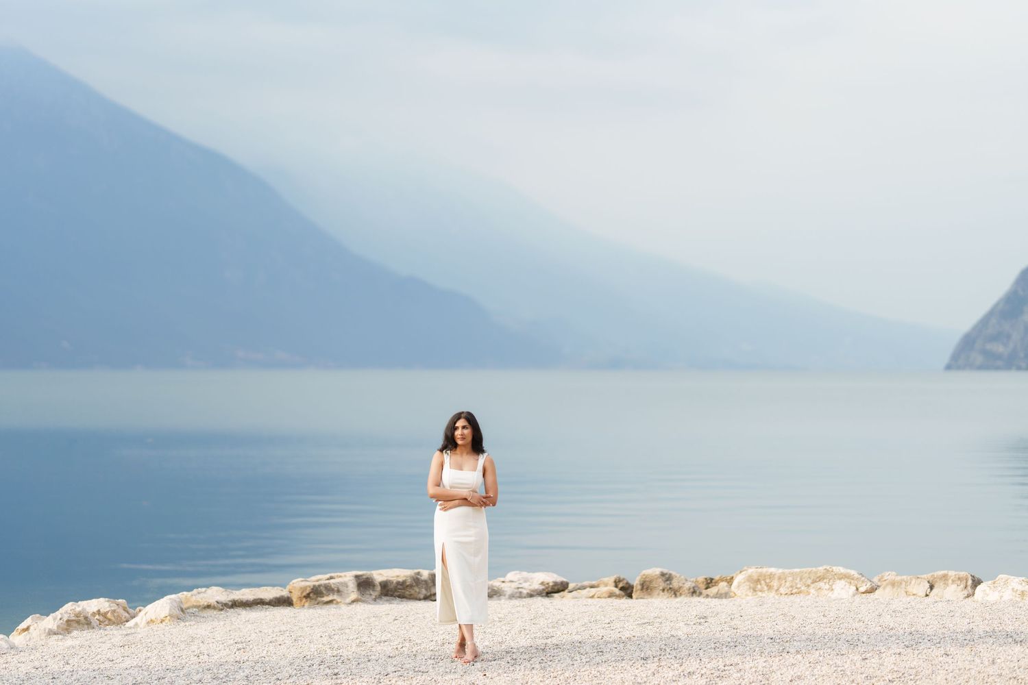 A scenic mountain lake view with rocky shoreline and misty peaks in the distance.