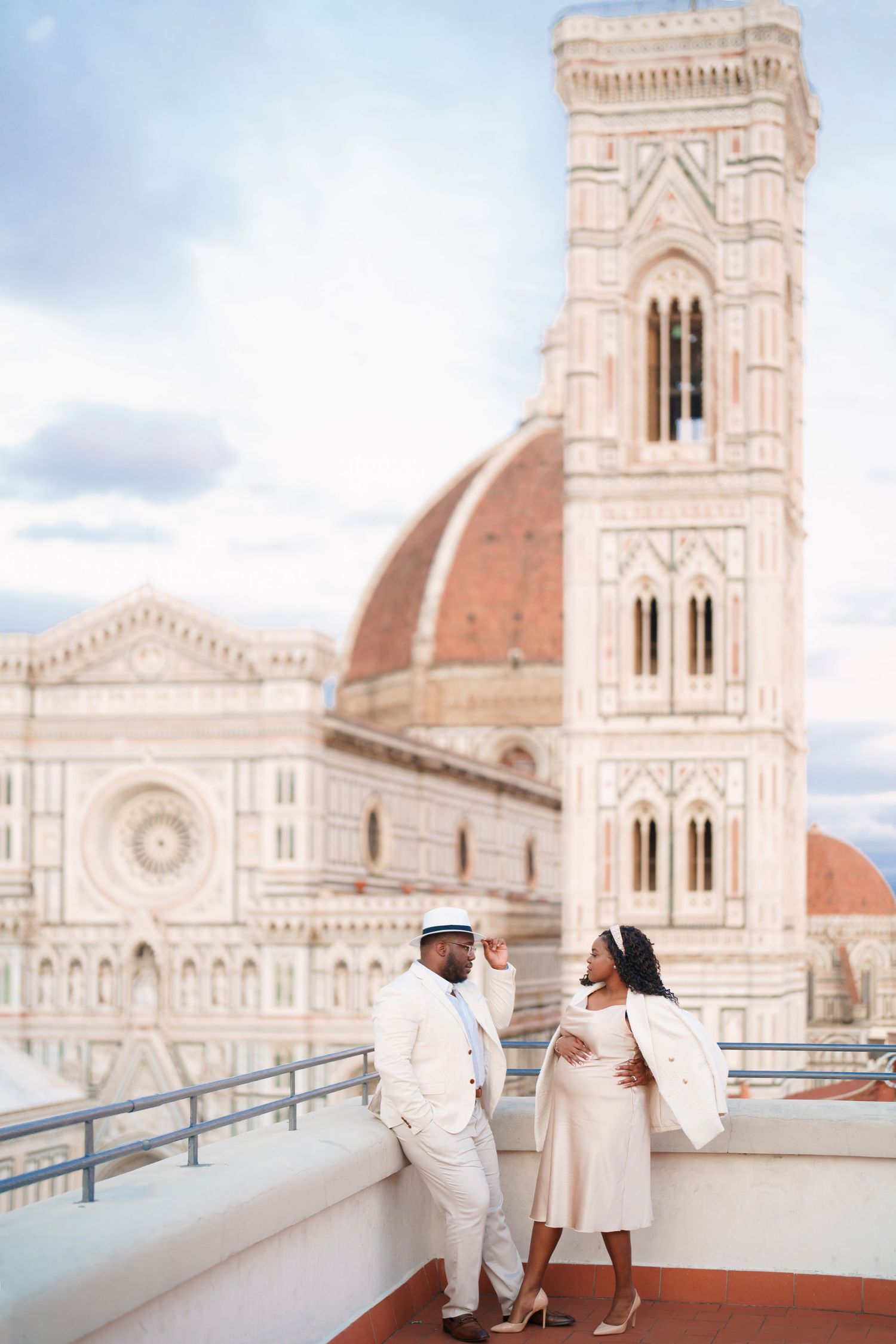 Couple posing on a rooftop terrace with Florence Cathedral and Giotto's Campanile in the background, Italy.