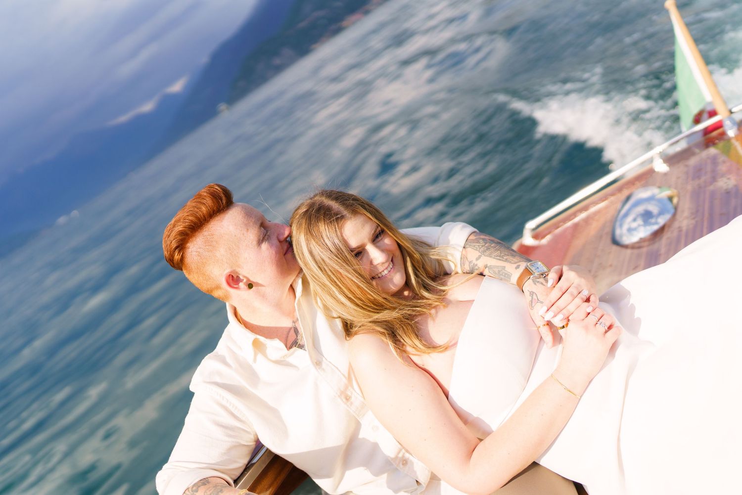 Couple embracing romantically on a luxury boat with blue ocean water in the background on a sunny day.