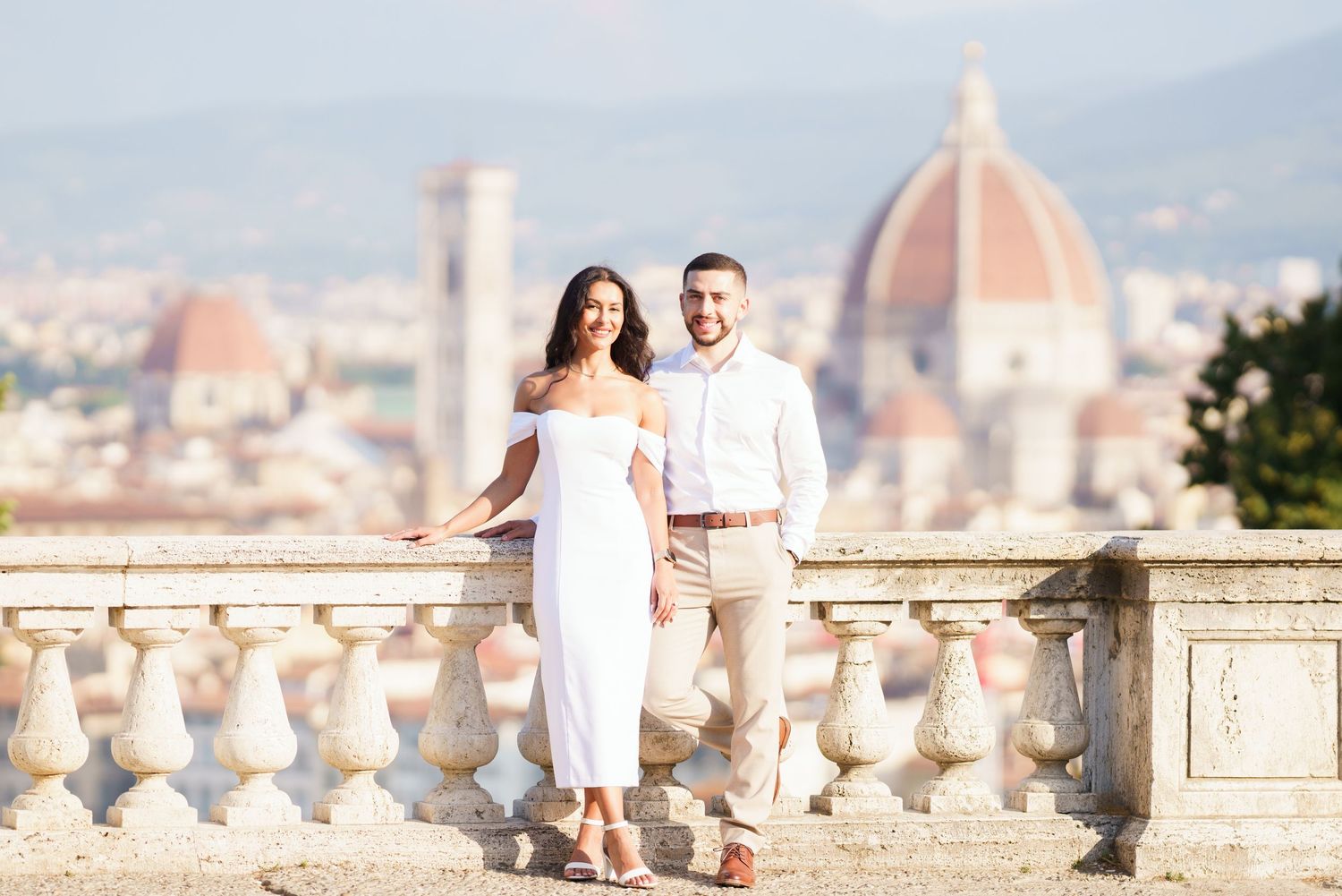 A couple poses on a terrace overlooking Florence with the iconic Duomo cathedral dome in the background.