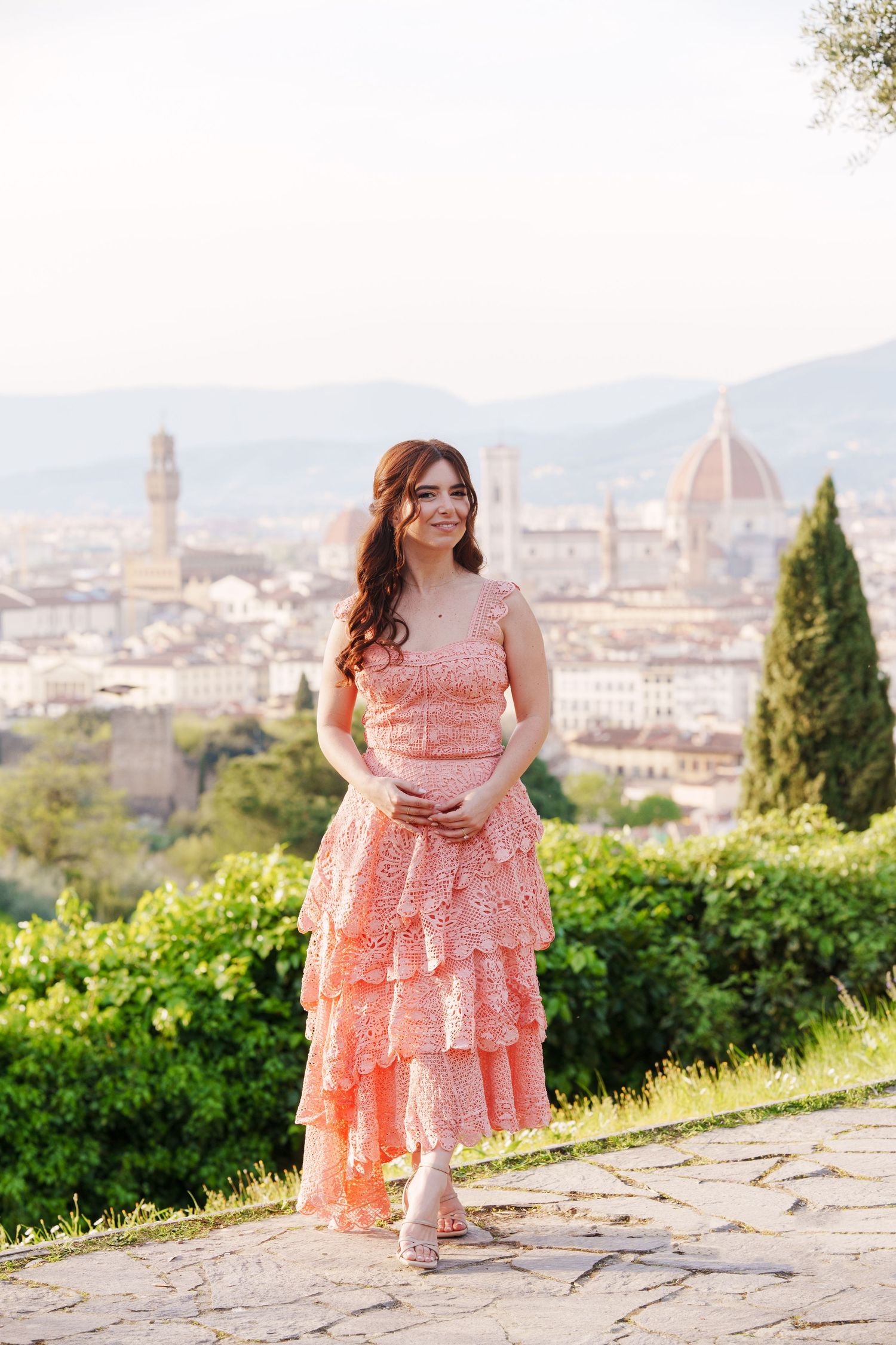 A peach lace dress flows in the breeze against the stunning backdrop of Florence, Italy with its iconic Duomo visible.