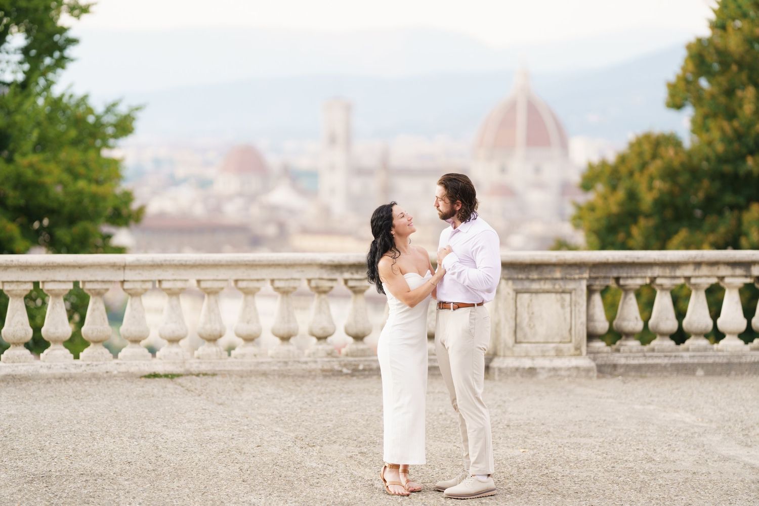 Romantic couple embraces on a stone balcony overlooking Florence, Italy during a dreamy sunset photoshoot.