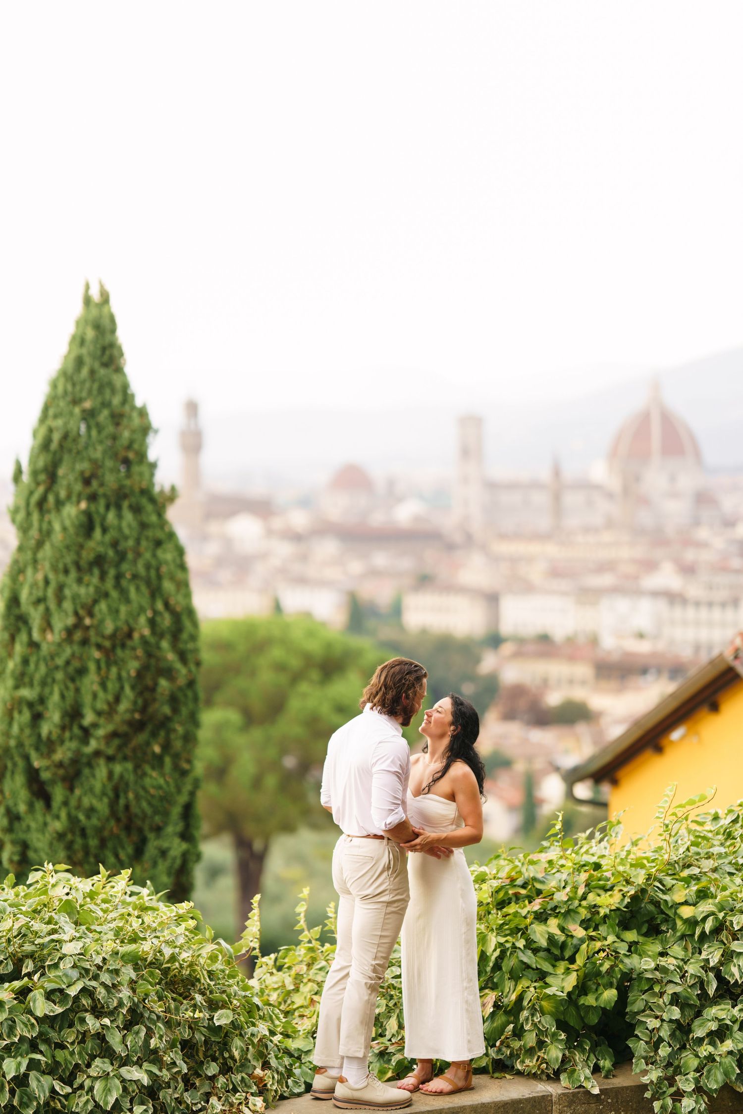 A romantic moment captured in a vineyard overlooking the historic skyline of Florence, Italy during golden hour.