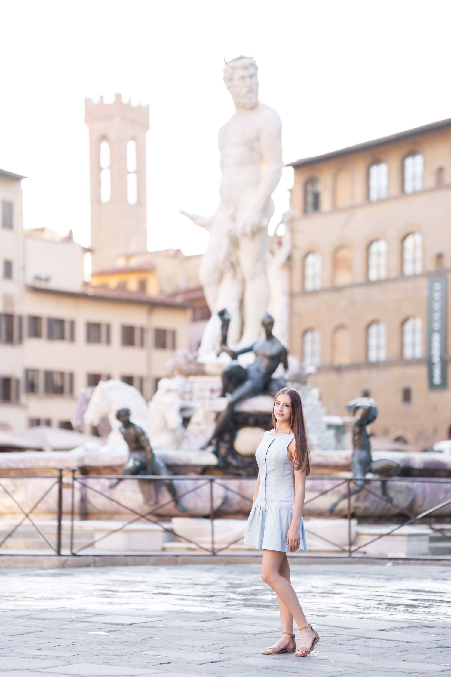Tourist in light blue dress poses near the Neptune Fountain in Piazza della Signoria, Florence, Italy.