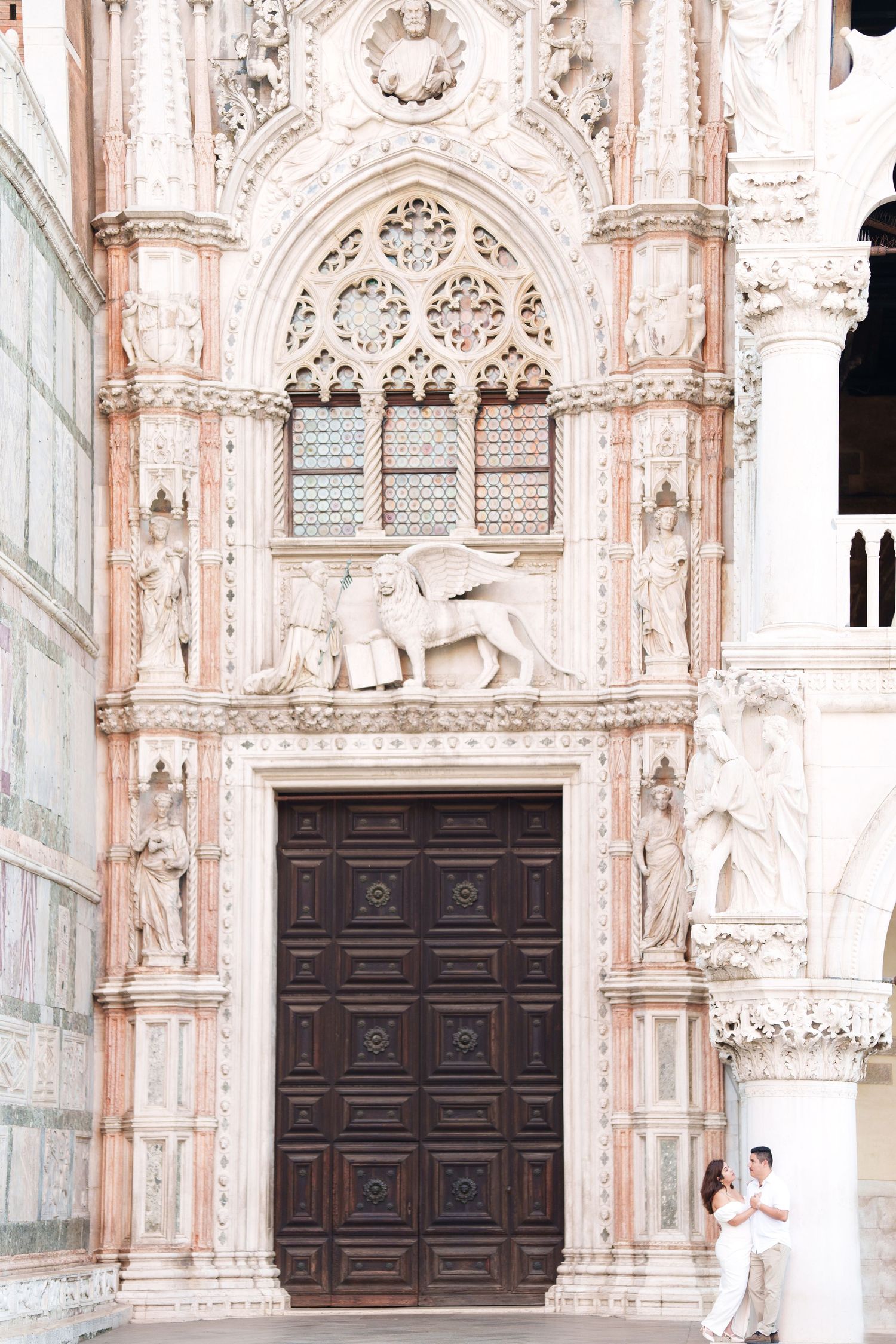Ornate Gothic doorway with carved stone details and winged lion sculpture at St. Mark's Basilica in Venice, Italy.