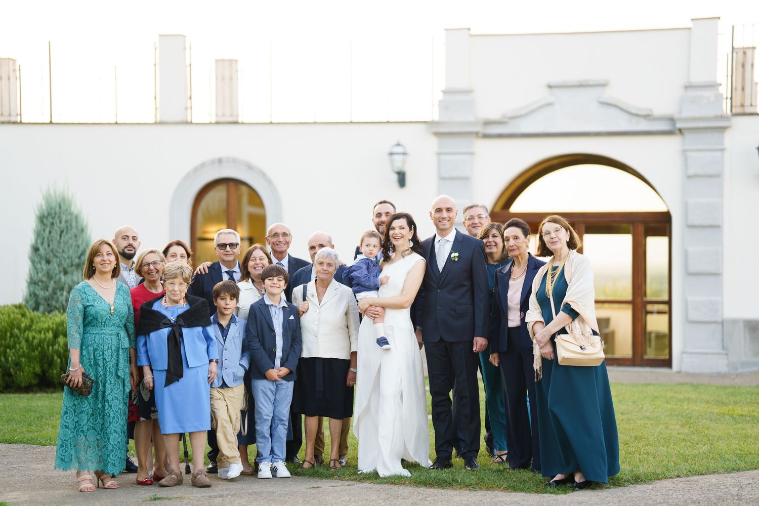 Large wedding group photo being taken outside white church with classic architecture.