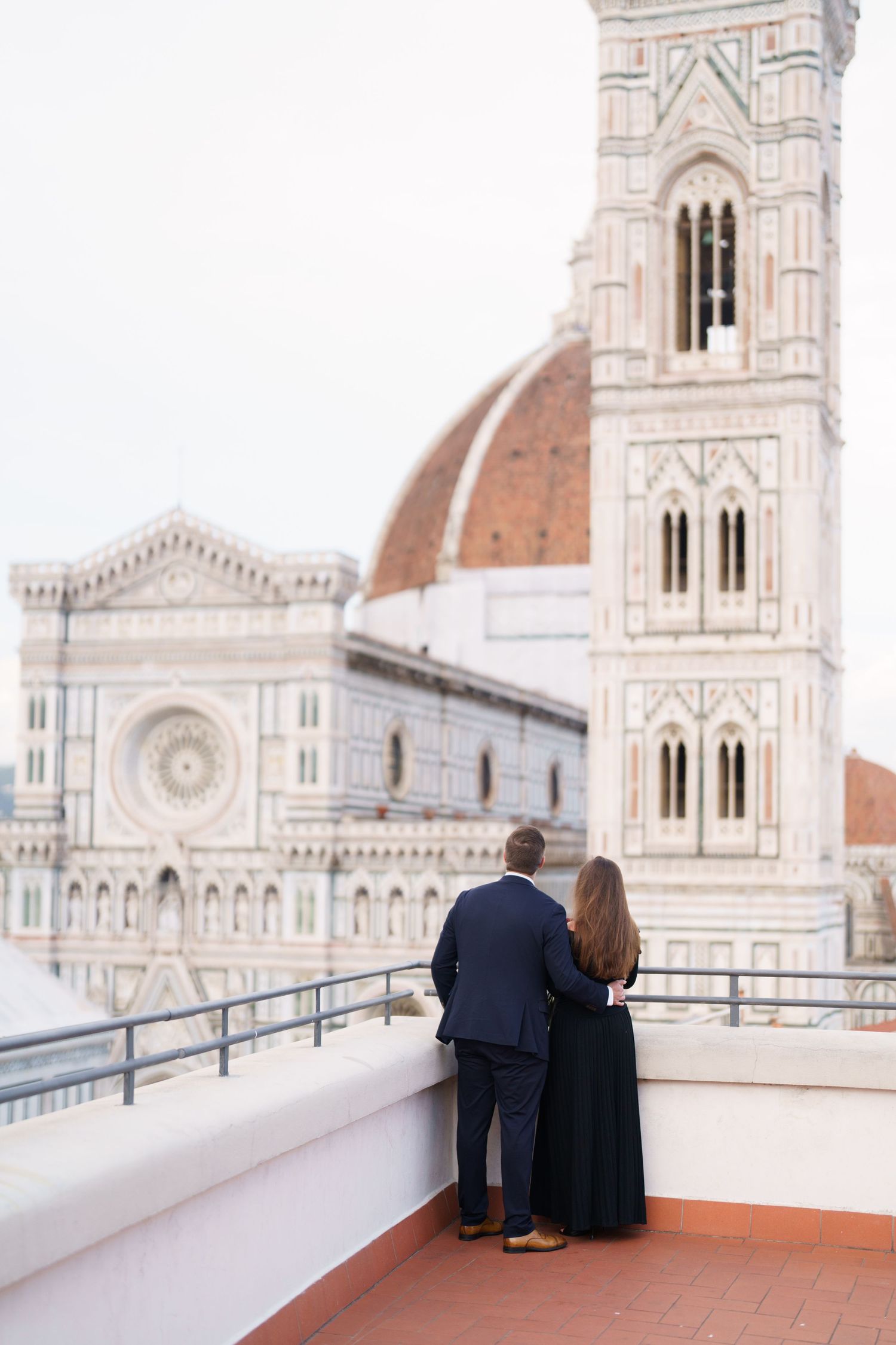 Two people admire the stunning Florence Cathedral and Duomo from a rooftop terrace in Italy.