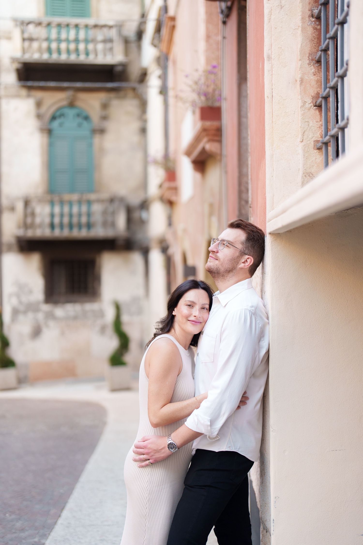 A couple in formal attire shares an intimate moment against a rustic Italian villa backdrop.