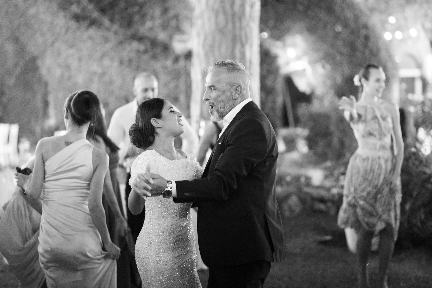 Wedding guests gather and socialize during an outdoor evening reception.