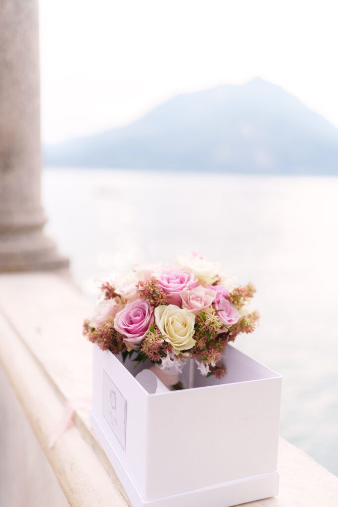 White box filled with pink and cream roses displayed on terrace with mountain vista.