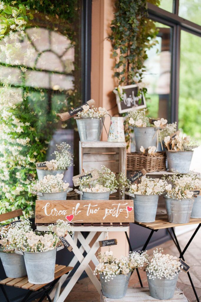 Wedding decor featuring white baby's breath in galvanized buckets on white wooden tables.