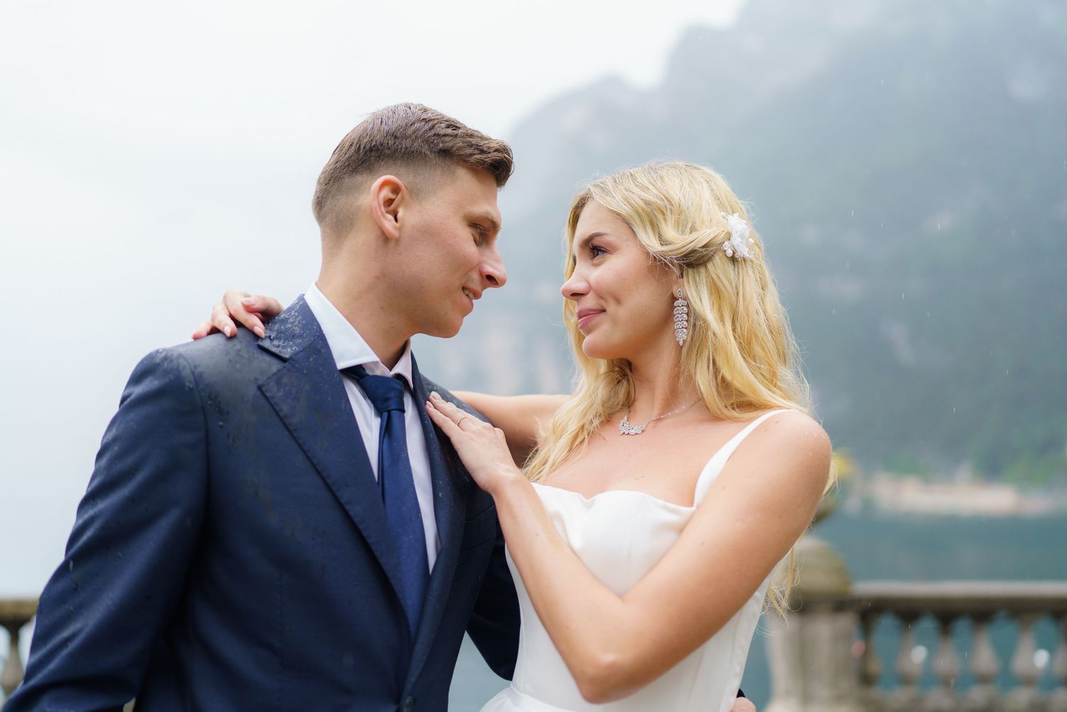A romantic wedding couple shares an intimate moment against a misty mountain backdrop at Lake Como.
