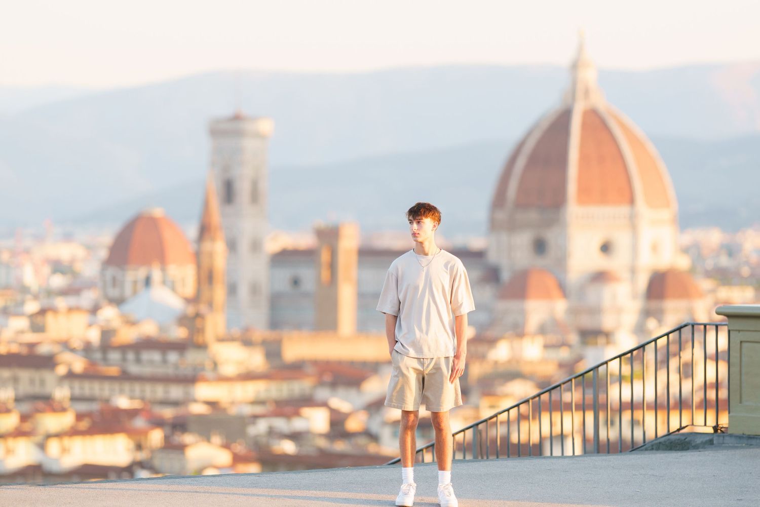 photographer Florence A person stands on a viewpoint overlooking Florence's historic skyline with the iconic Duomo cathedral dome at sunset.