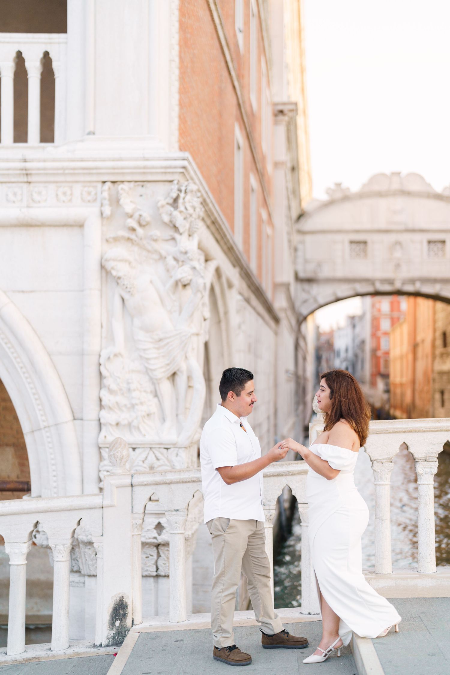 A romantic couple shares tender moments against the backdrop of Venice's ornate Doge's Palace architecture.