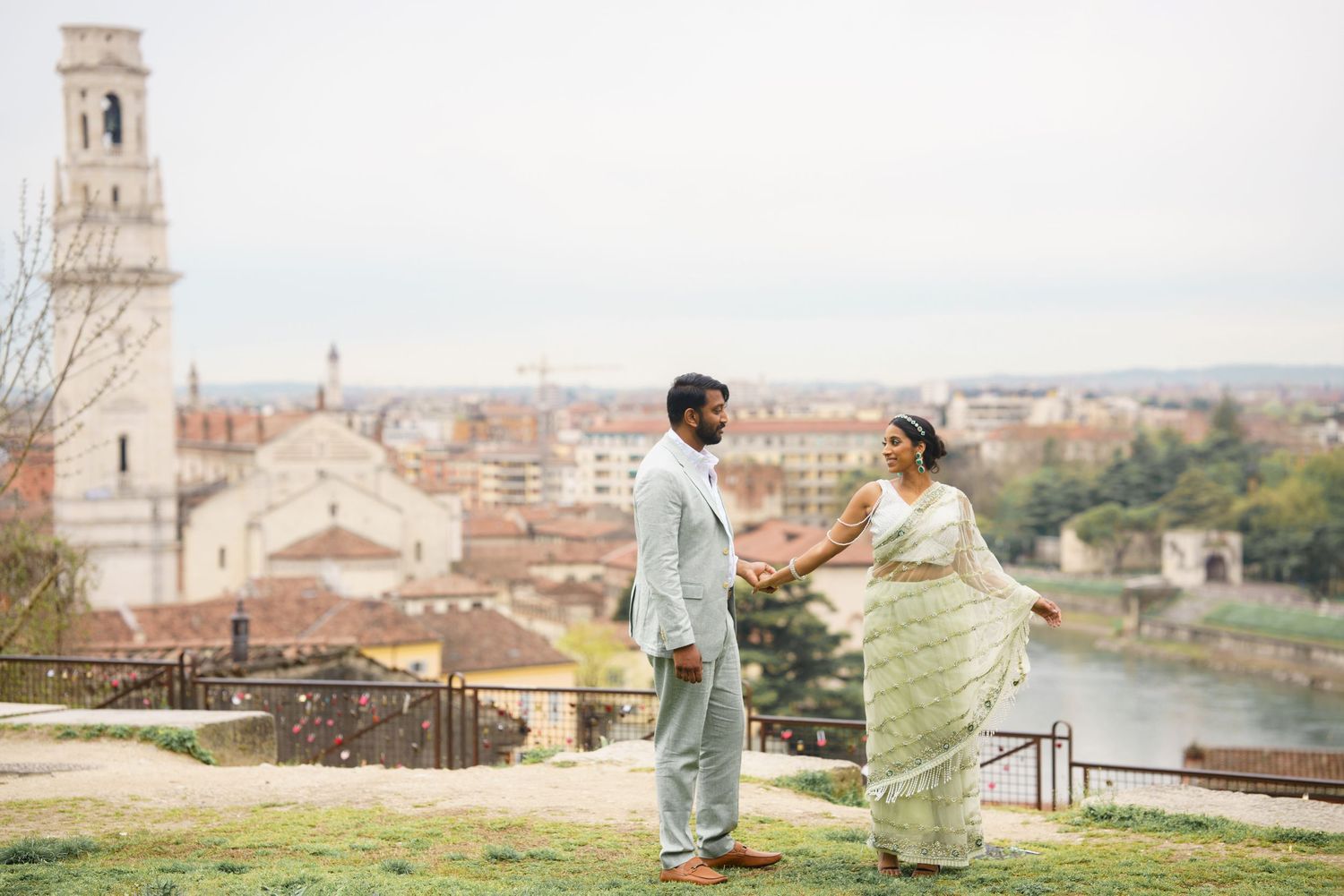 A couple stands on a scenic overlook with historic buildings and towers in Florence, Italy during golden hour.