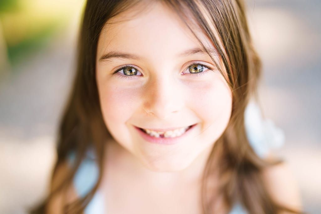 A collage of smiling faces with bright expressions and warm lighting.