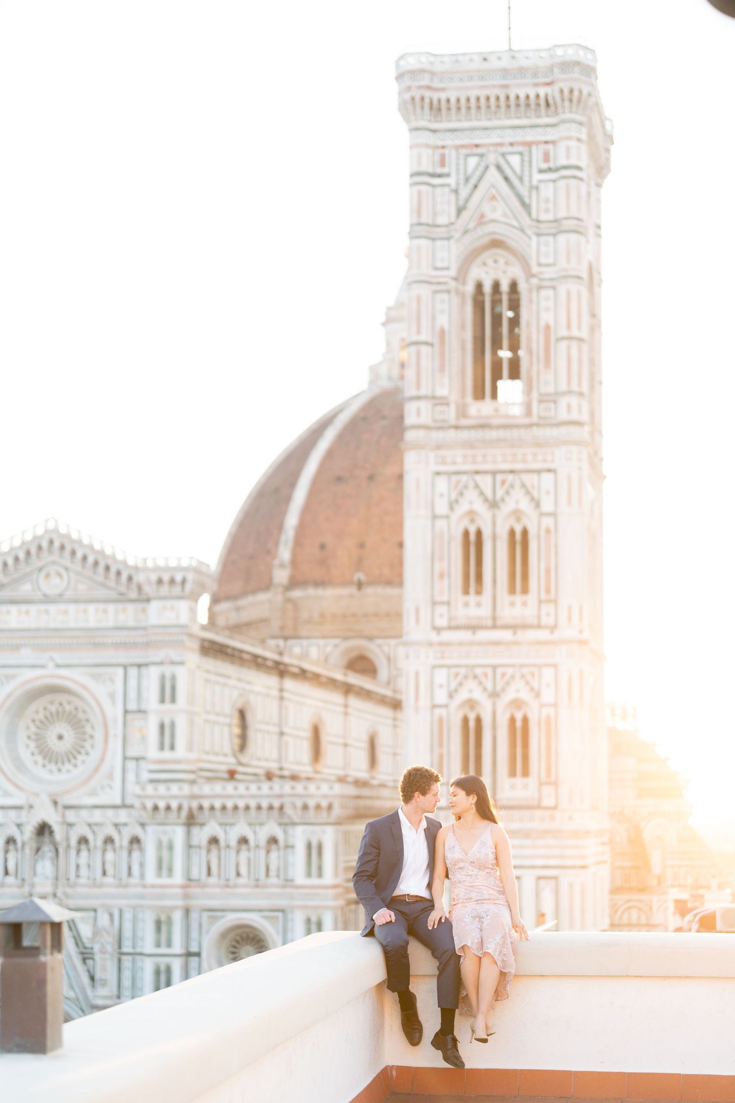 A couple shares a romantic moment at sunset in front of Florence Cathedral's iconic marble facade and dome.