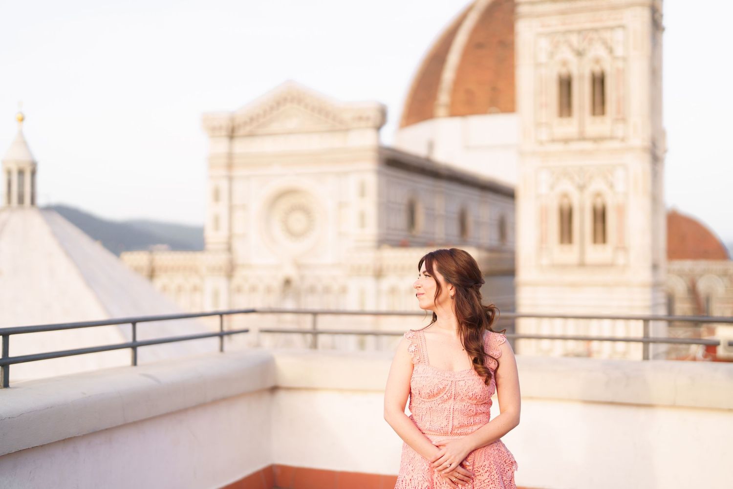 Bride in a pink tulle gown poses elegantly in front of a grand European cathedral during sunset.