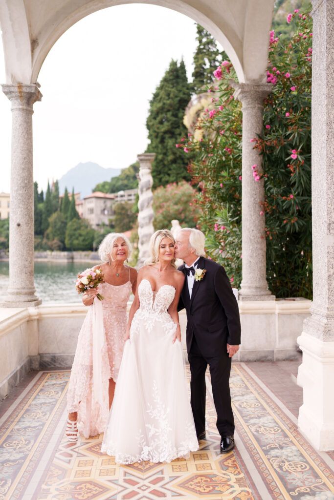 Wedding ceremony taking place under elegant white stone arches with mountain views and floral decorations.