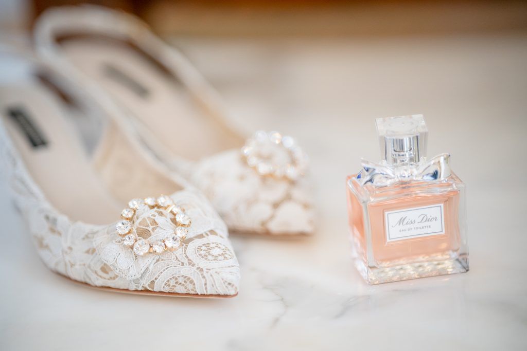Wedding accessories including crystal perfume bottles and embellished bridal shoes on light background.