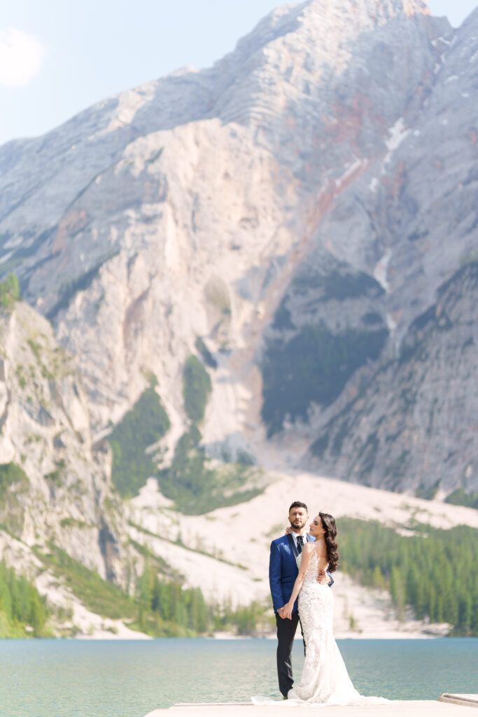 Intimate wedding moment captured on a dock with stunning Dolomite mountains and lake views.