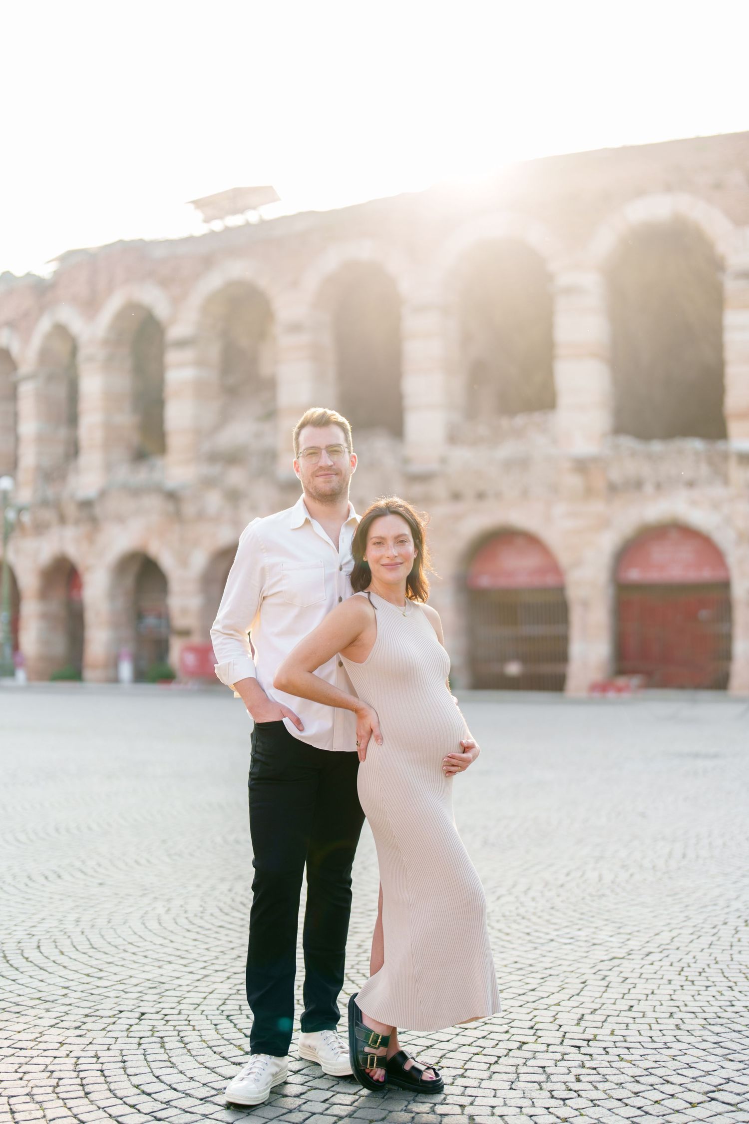 Verona photographer A couple poses together in front of historic stone arches during a romantic photoshoot at sunset.