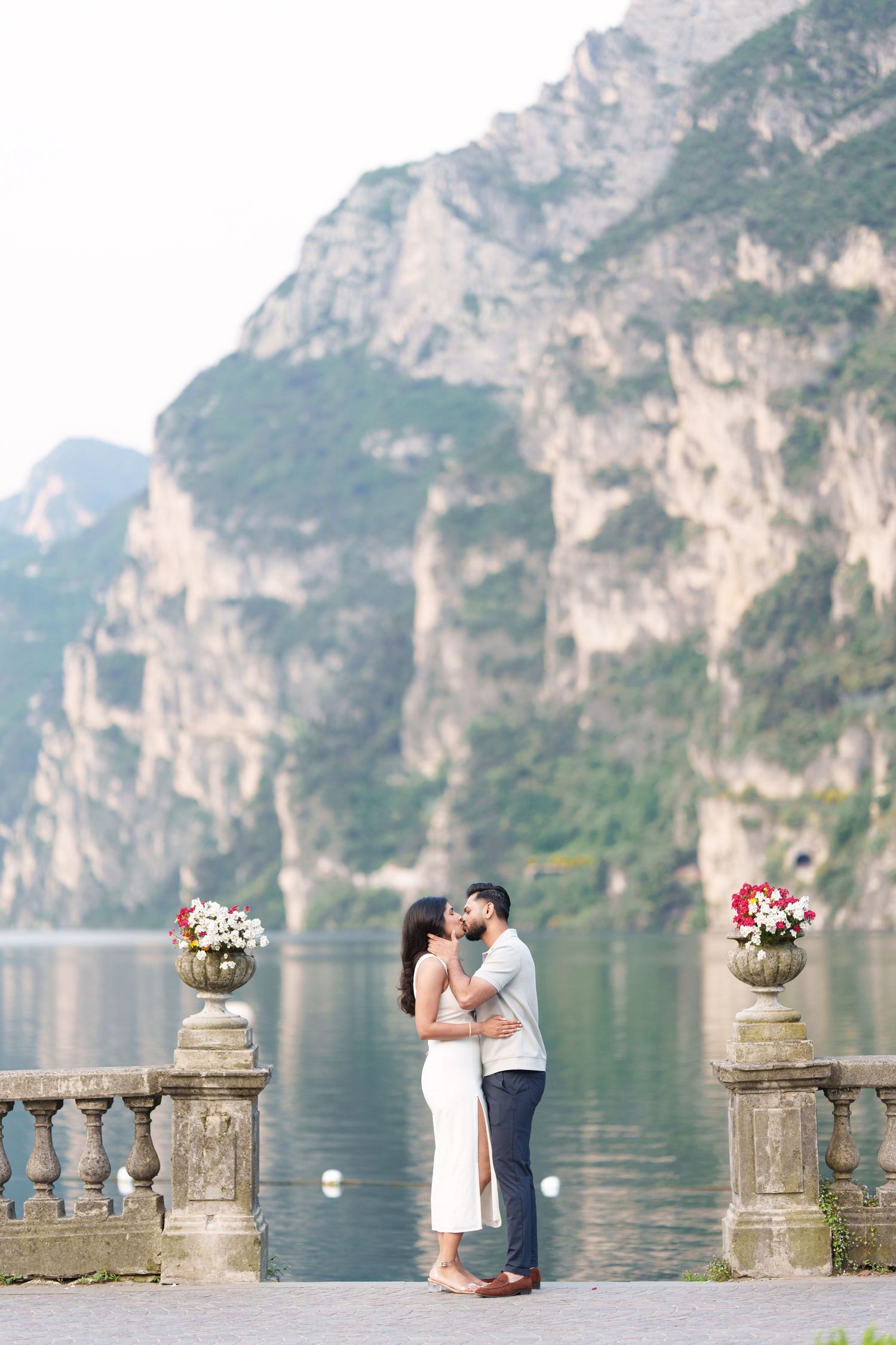 Romantic couple photoshoot at Lake Garda with stunning mountain cliffs and stone balustrades along the waterfront.