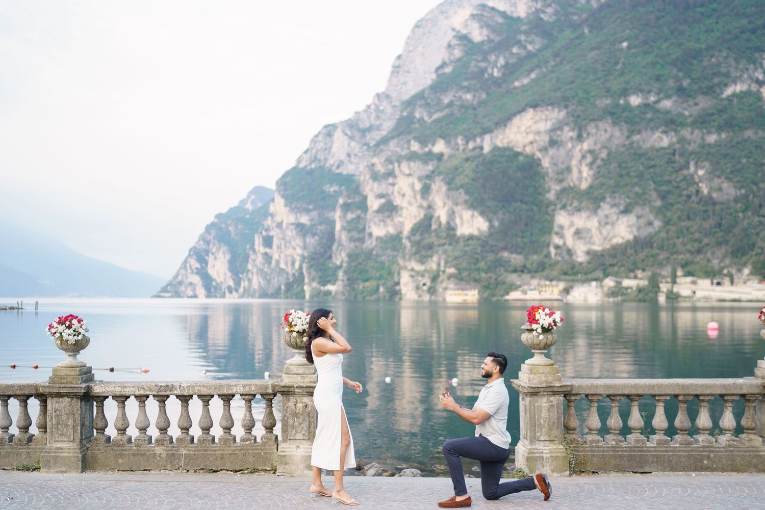 Couple shares romantic moments along scenic Lake Como in Italy with mountains and lake views in the background.