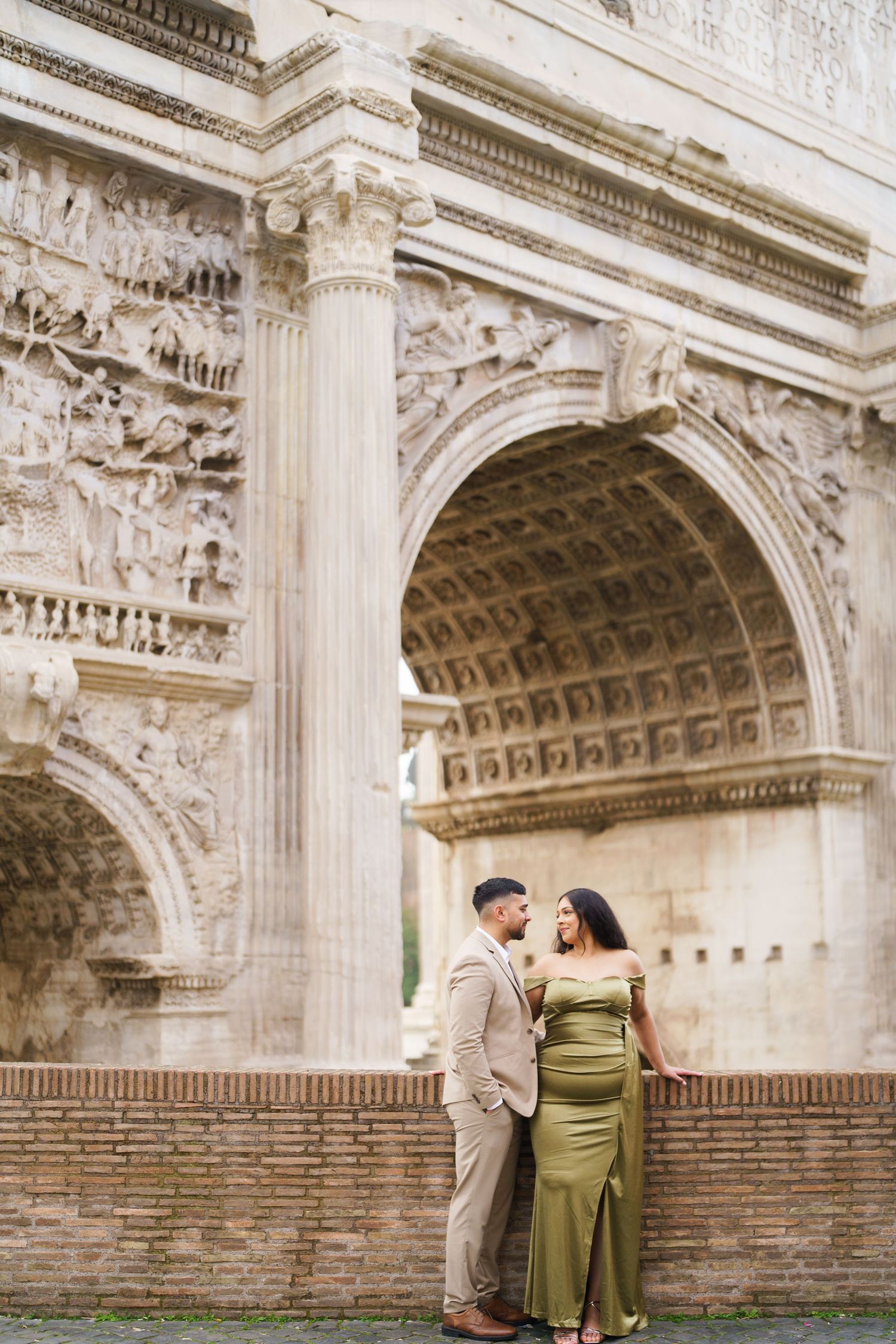 Couple posing romantically in front of the Arch of Septimius Severus in Rome, Italy.