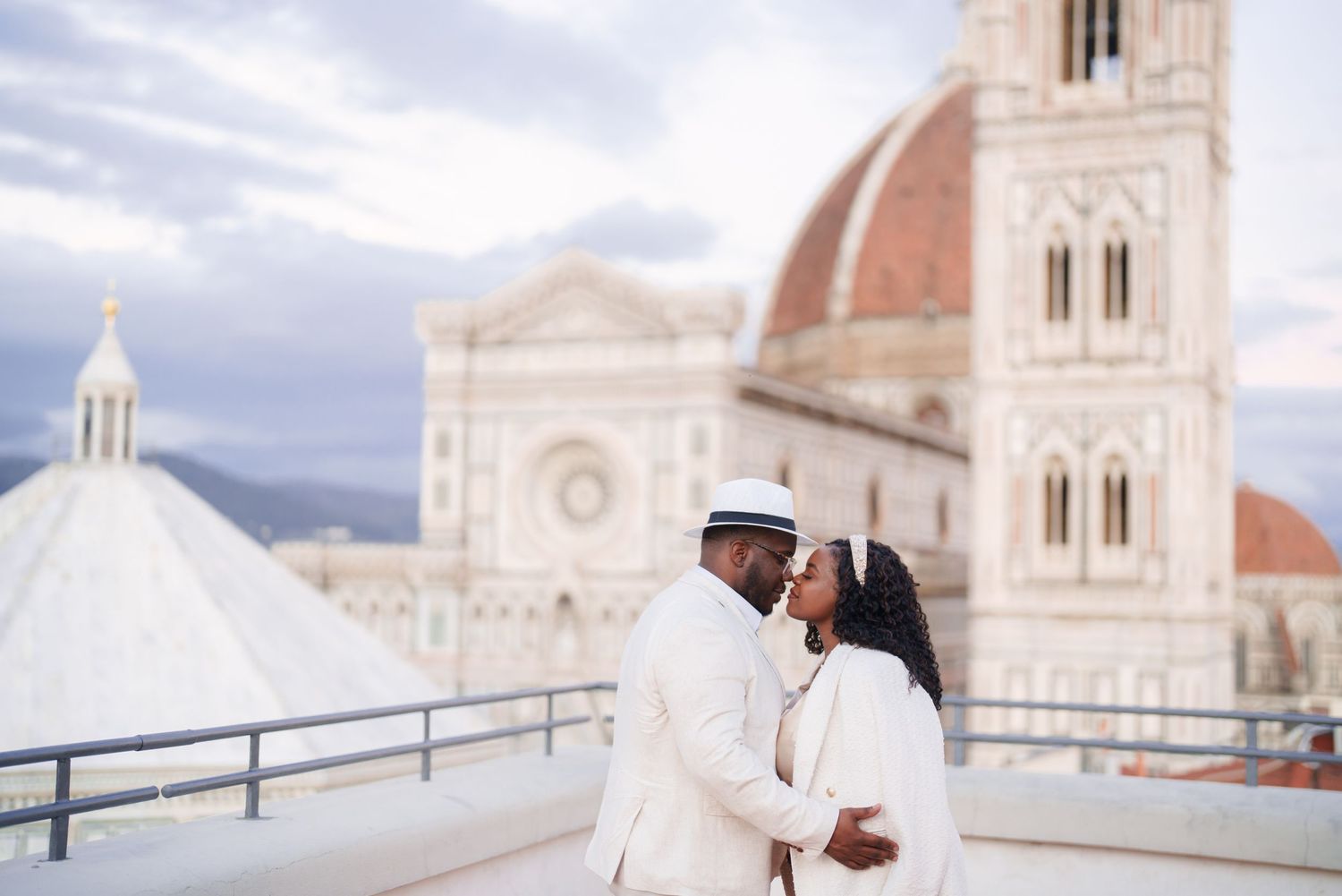 Couple sharing a romantic moment on a rooftop with Florence Cathedral dome backdrop in Italy.