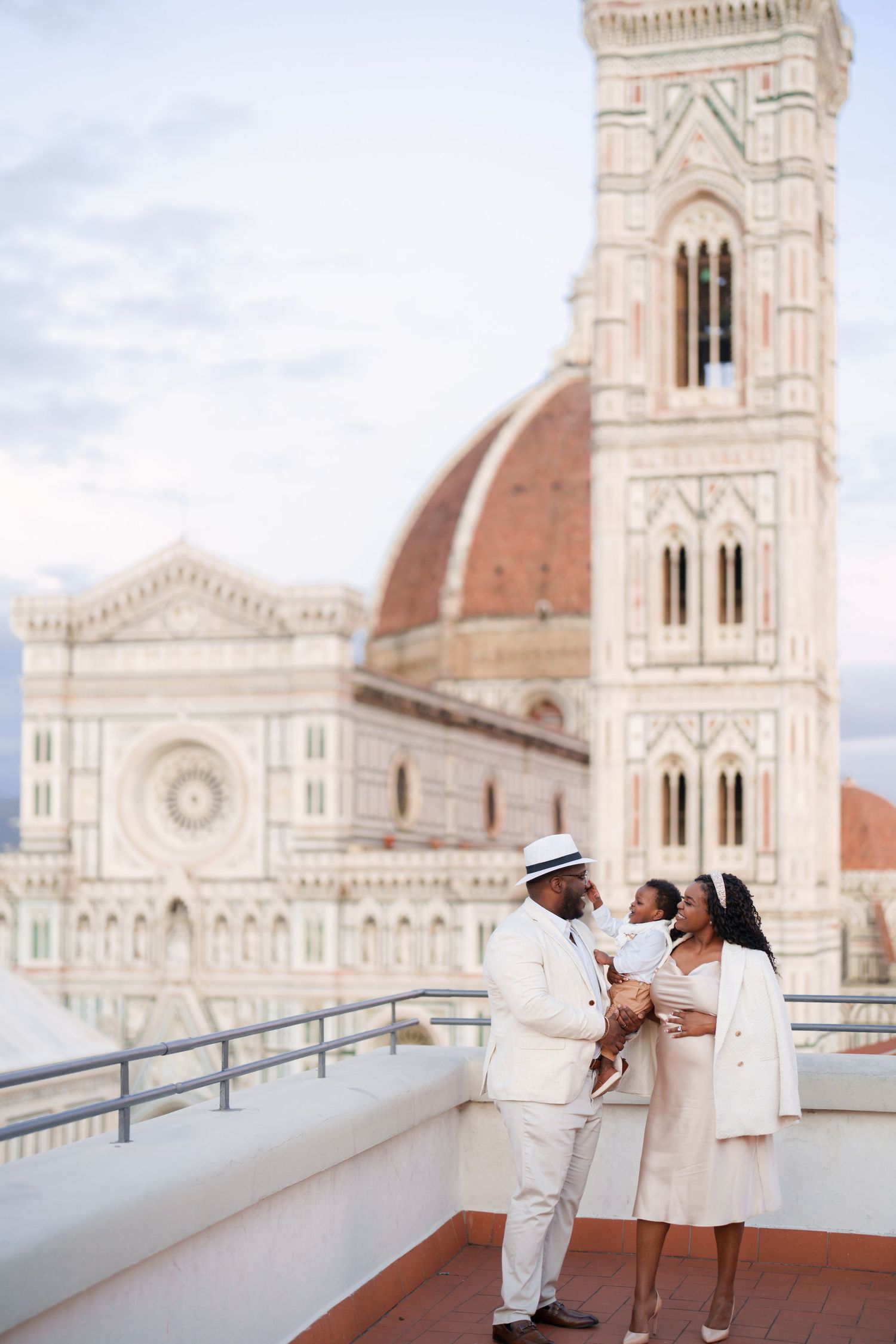 A family poses on a rooftop terrace with Florence Cathedral's iconic dome and Giotto's Campanile in the background.