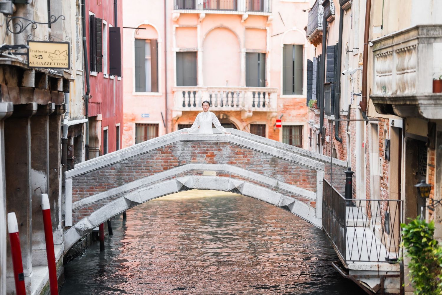 A charming stone bridge spans a narrow Venetian canal lined with colorful historic buildings in Venice, Italy.