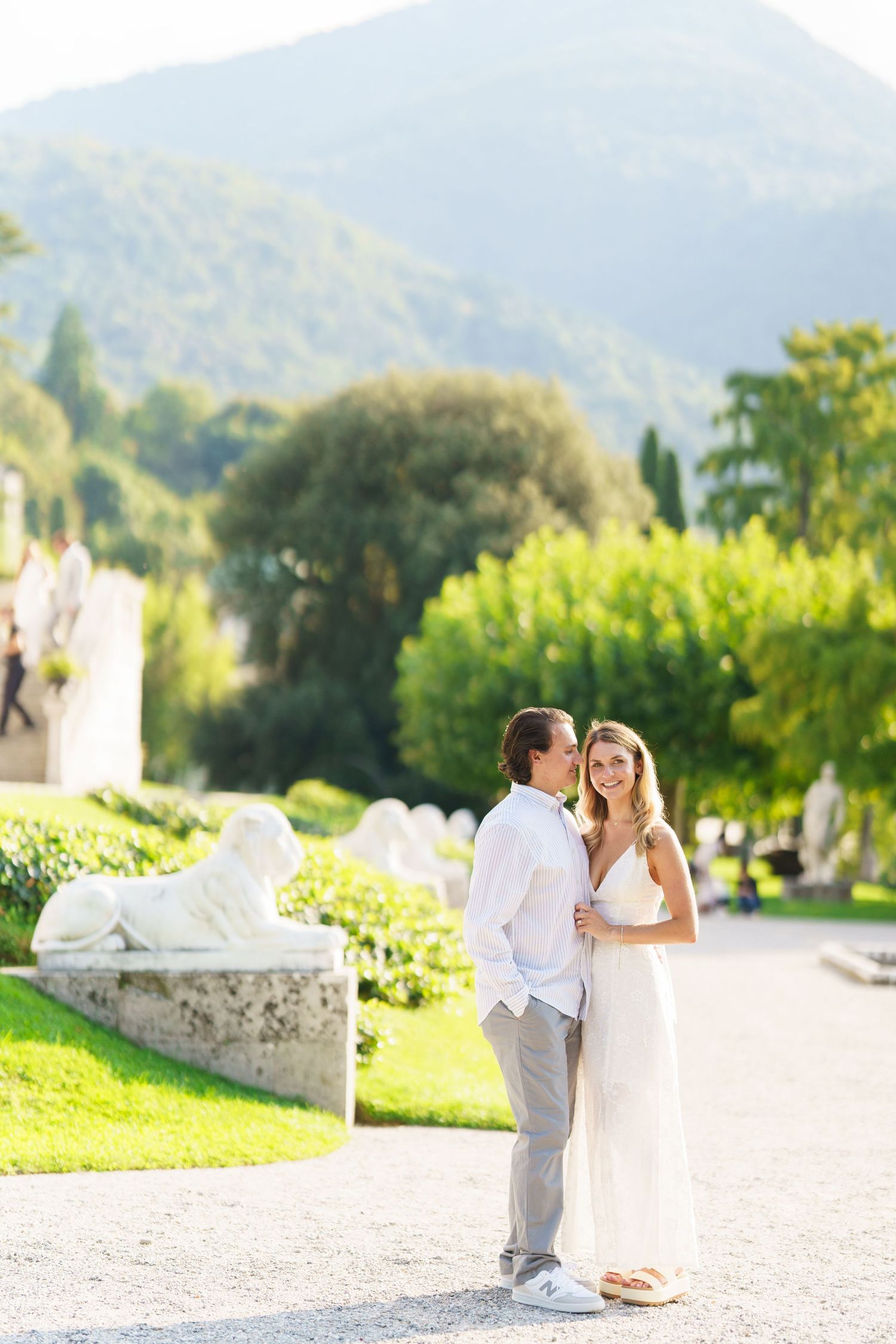 Bride and groom share intimate moments in a sunlit vineyard setting with mountains in the background.