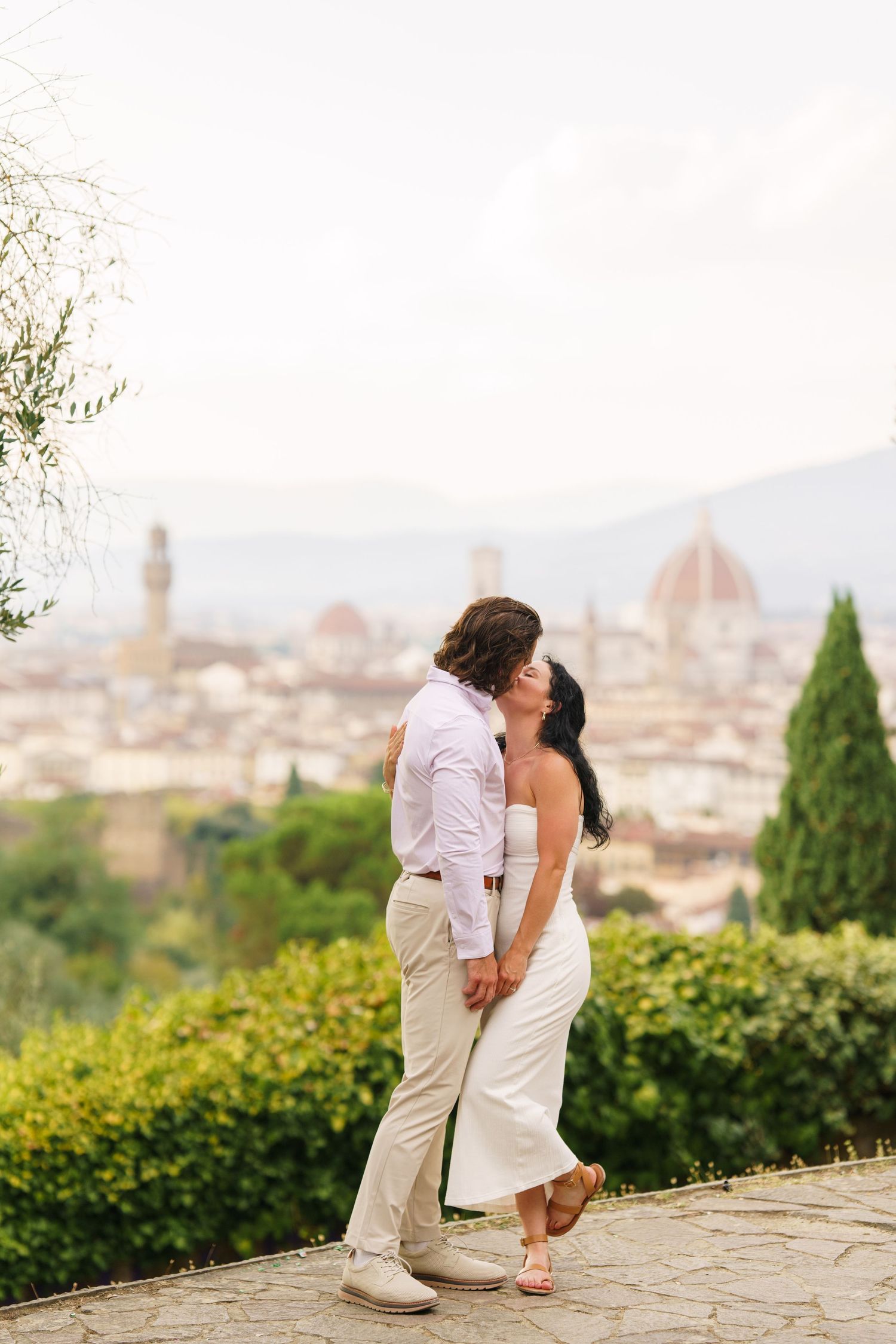 Romantic couple sharing a kiss with Florence's iconic Duomo cathedral and cityscape in the background.