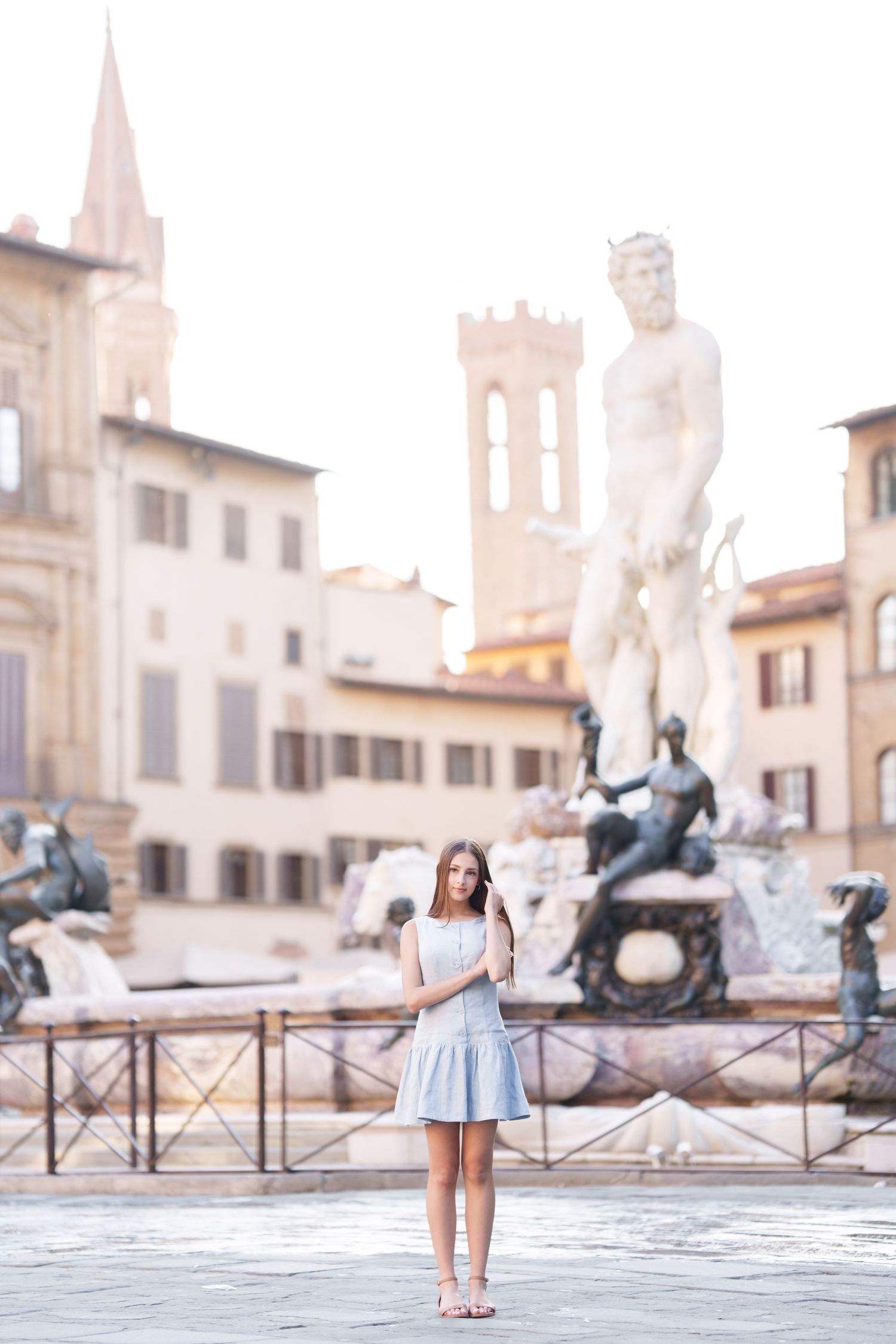 A person in a blue dress poses in front of the historic Fountain of Neptune in Florence's Piazza della Signoria.
