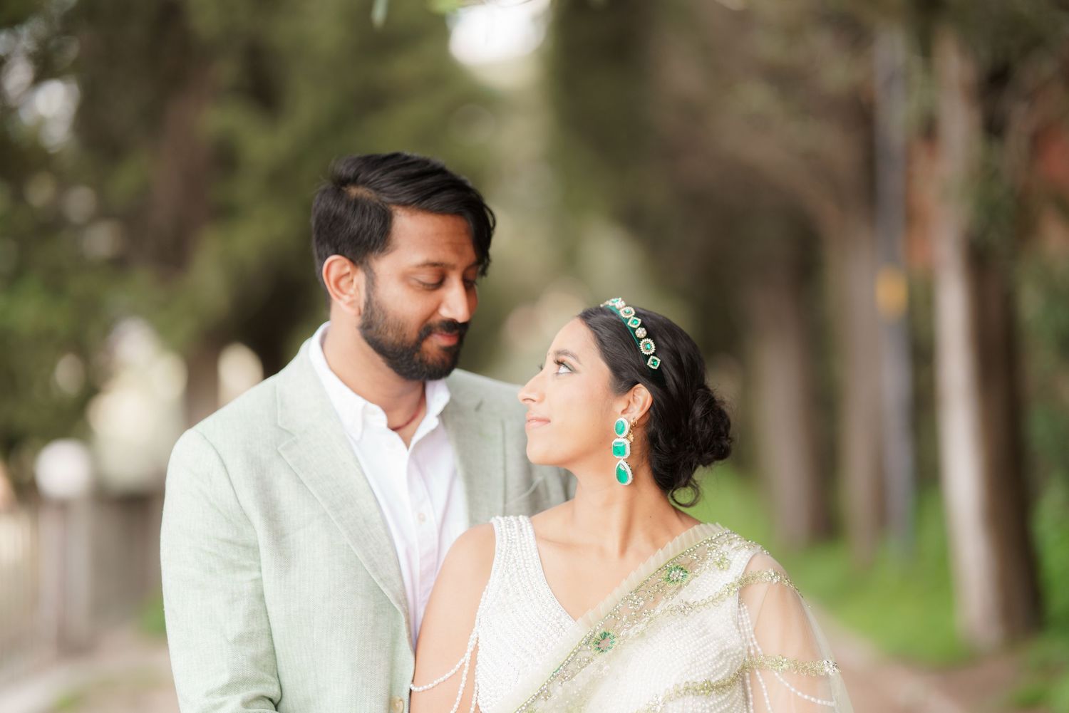 A couple in traditional Indian wedding attire share intimate moments in a garden setting during their wedding photoshoot.