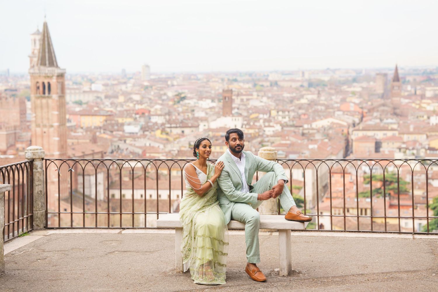 Couple enjoying scenic city views from elevated terrace overlooking historic European rooftops and church spires.