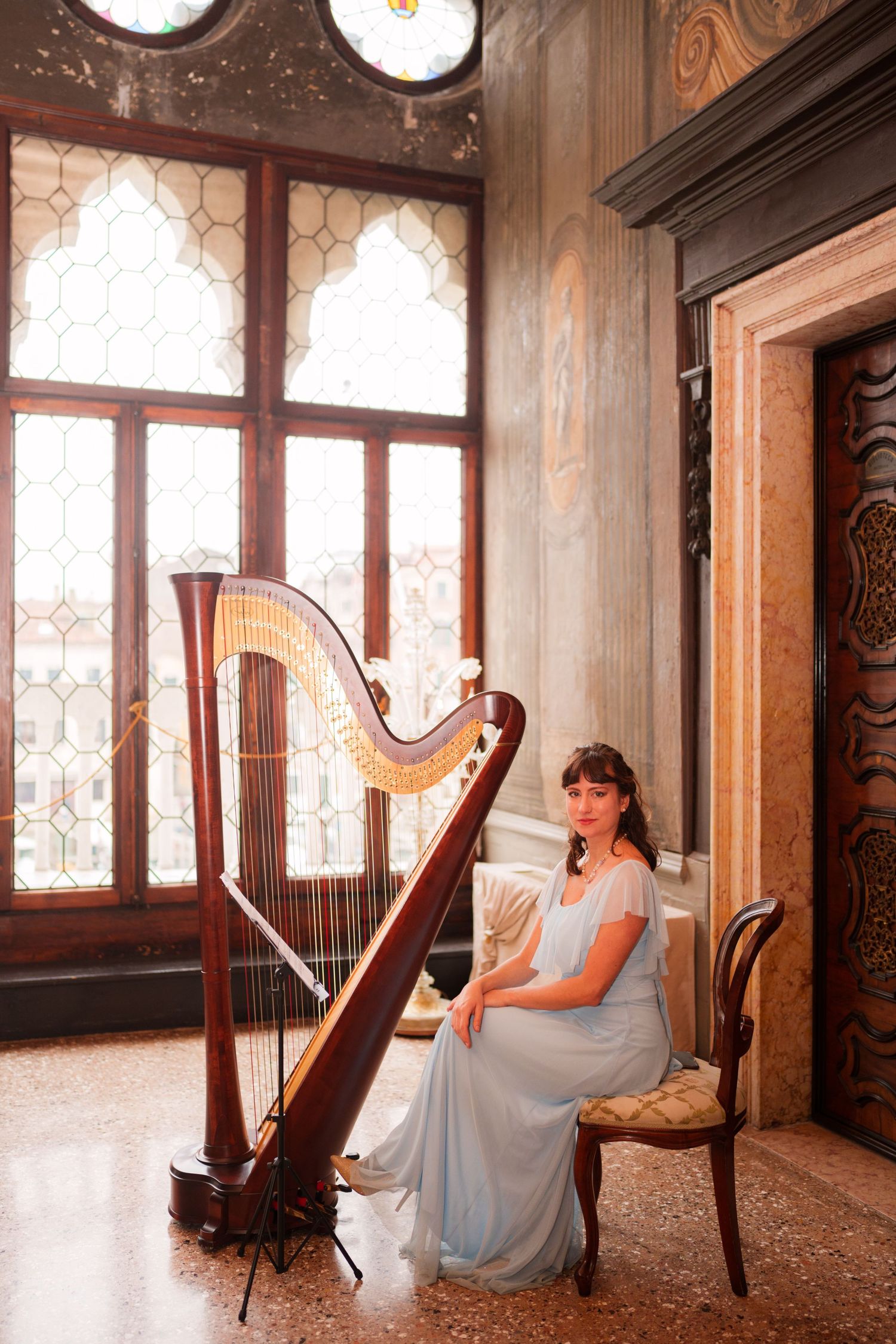 A series of artistic photos showing a harpist in a flowing blue dress performing in an elegant vintage room with leaded windows.