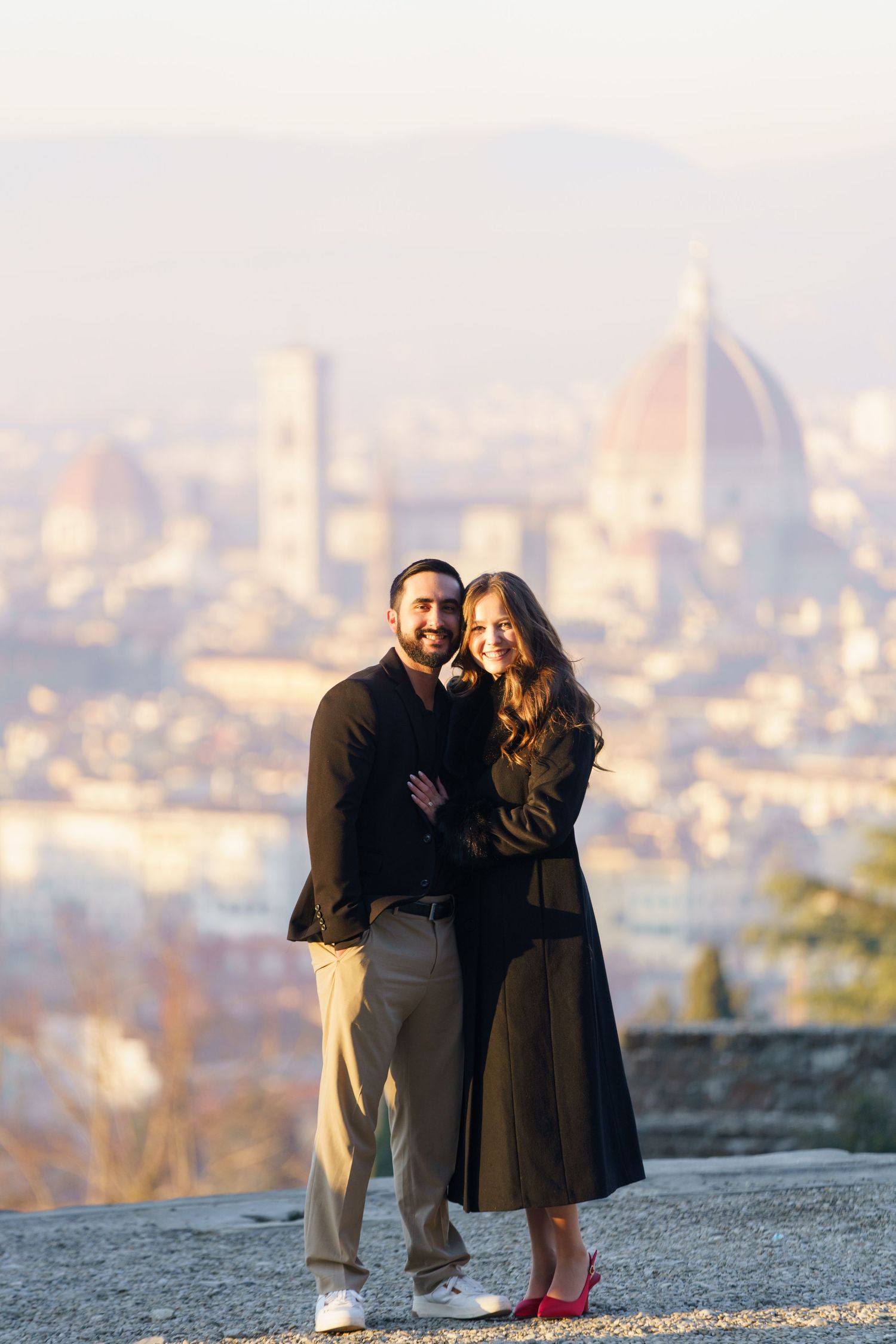 A couple poses together overlooking the iconic Florence skyline with the Duomo cathedral visible in the background.