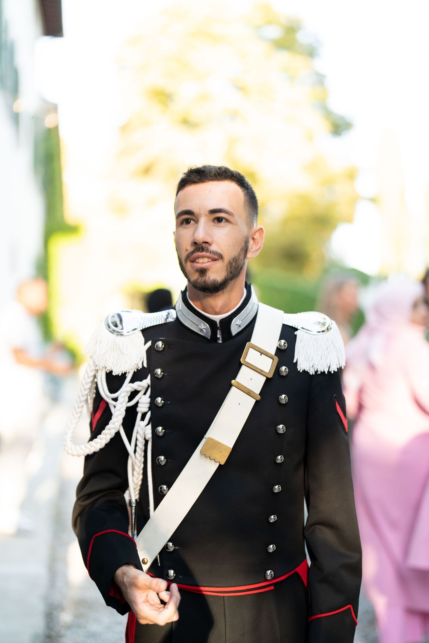 Military officer in formal dress uniform with white sash and medals at formal event.