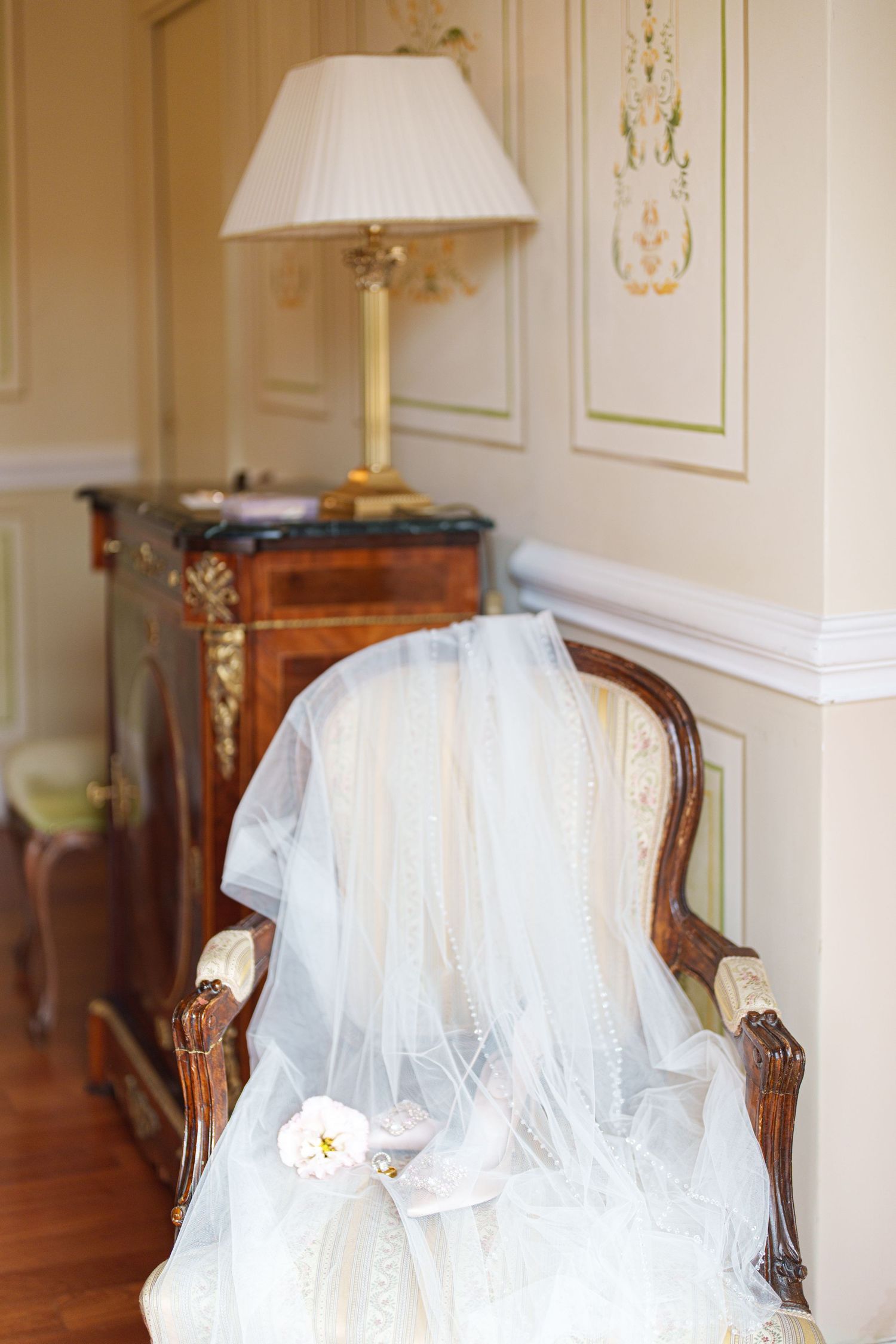 White tulle veil draped over an antique wooden chair in an elegant interior.