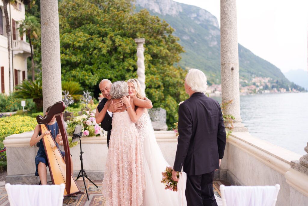 Wedding ceremony setup with harp musician under lakeside colonnade.
