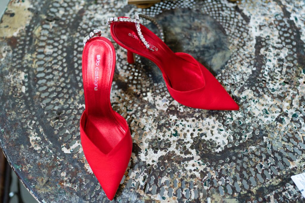 Close-up of red designer high heel shoes on ornate metallic surface.