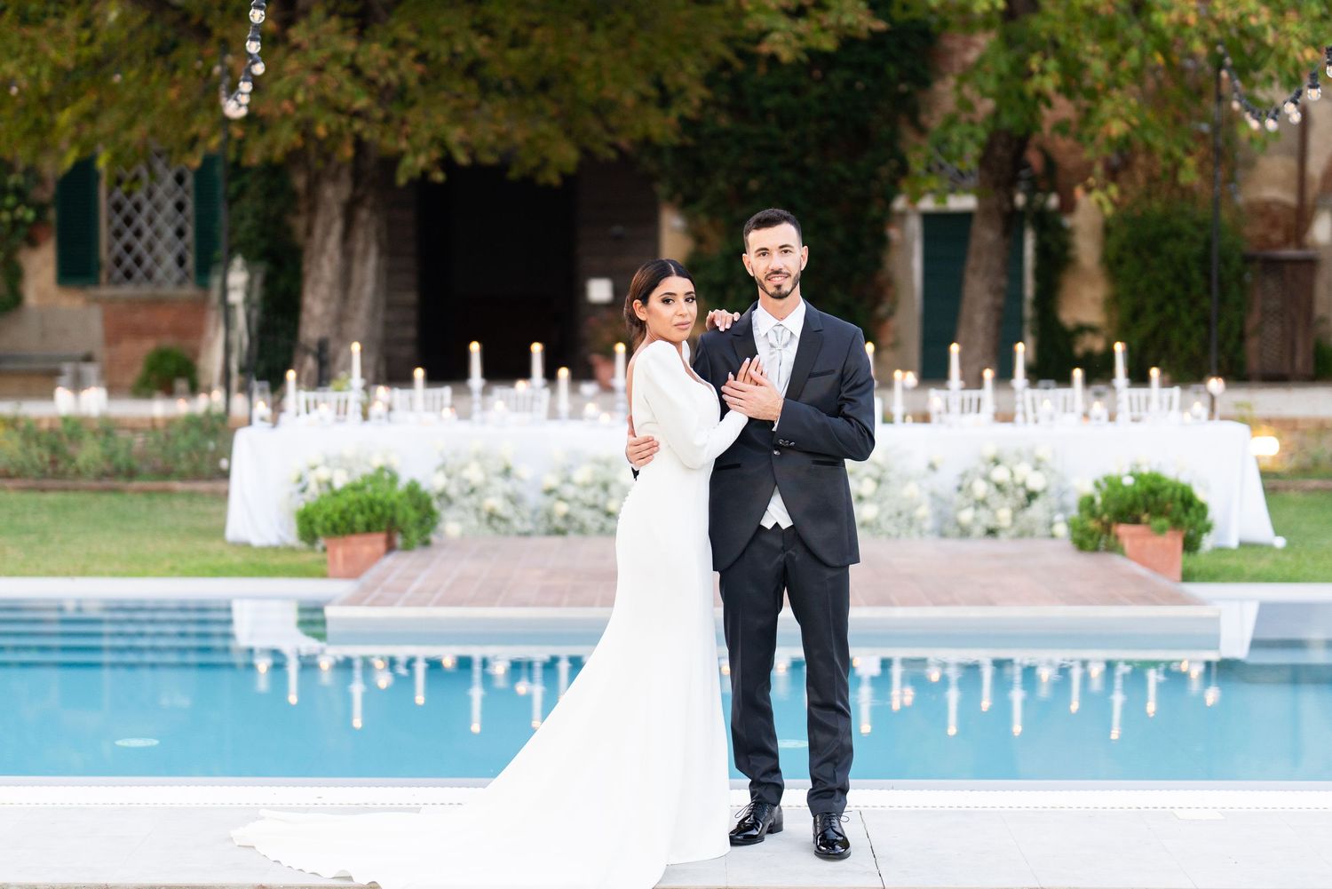 Wedding celebration setup with white decor and pool in background.