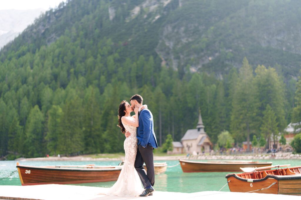 Wedding photos by mountain lake with wooden boats and alpine scenery.