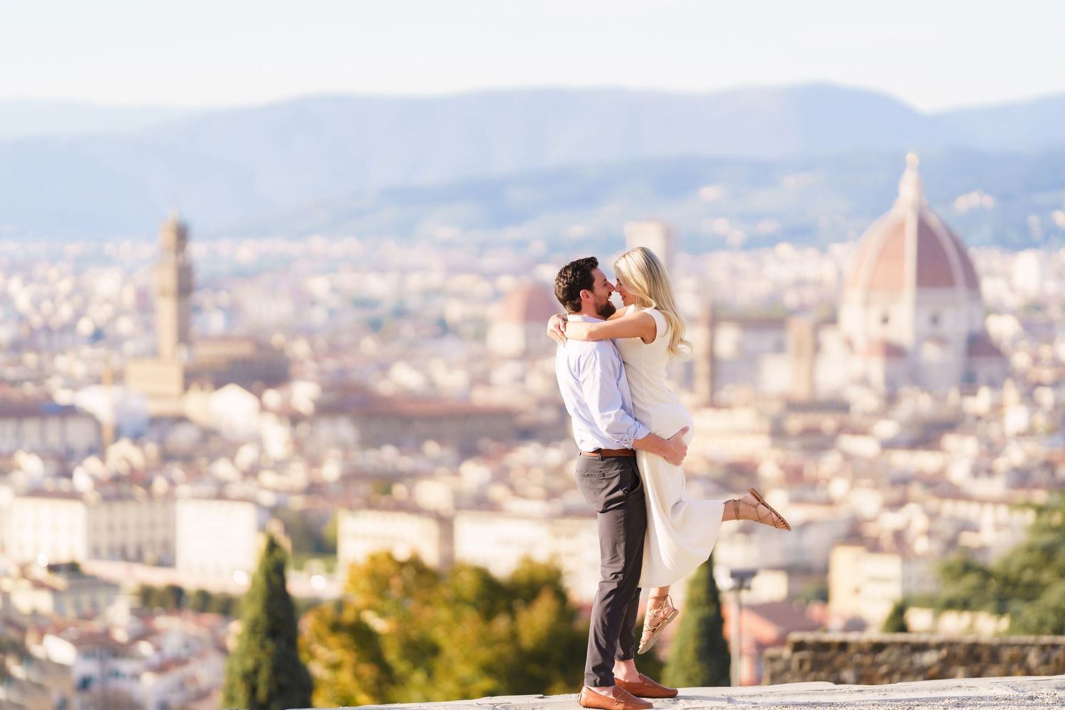 A couple shares a romantic moment overlooking Florence, Italy with the iconic Duomo cathedral in the background.