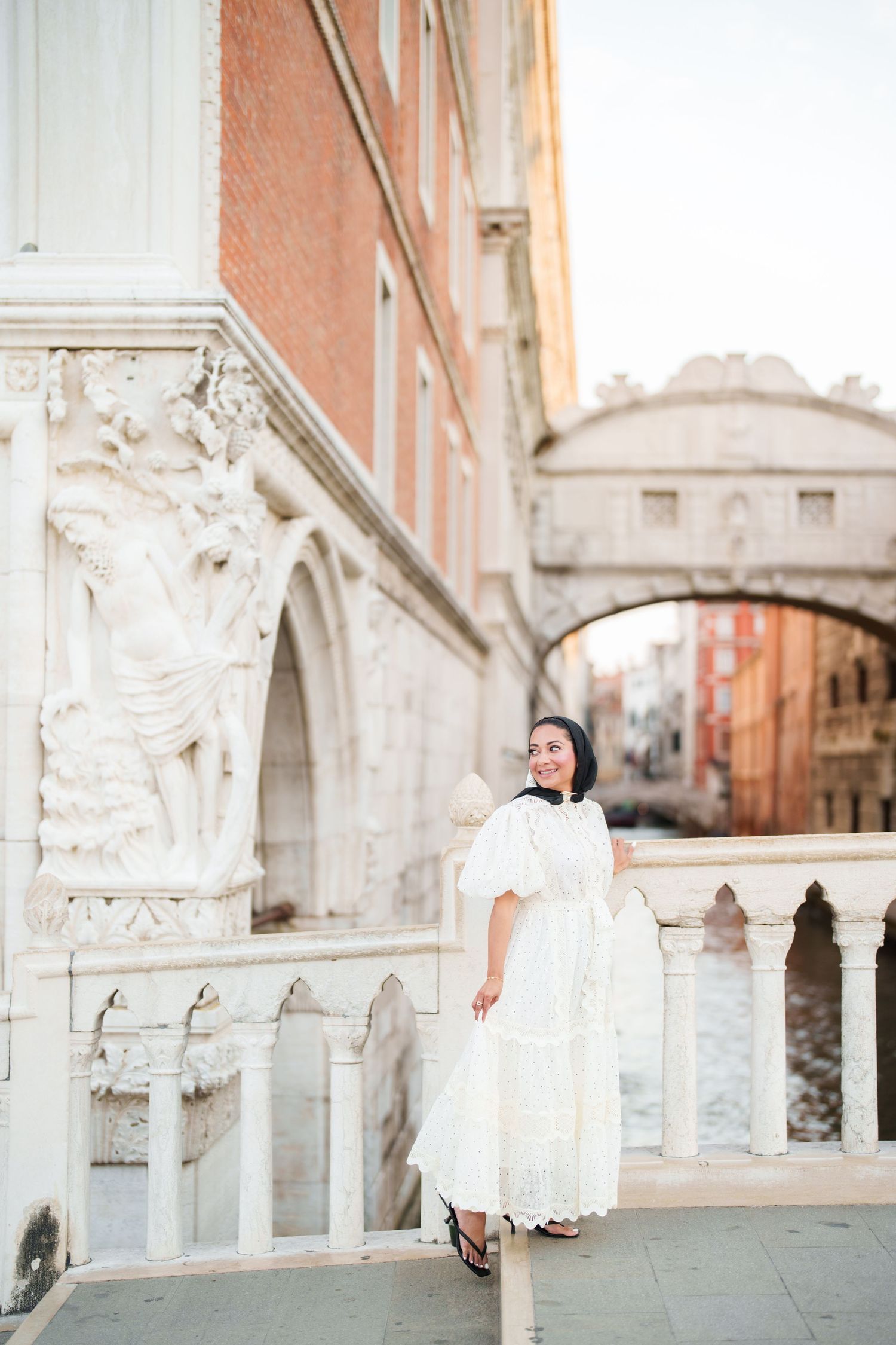 Woman in white dress posing near the Bridge of Sighs in Venice, Italy.